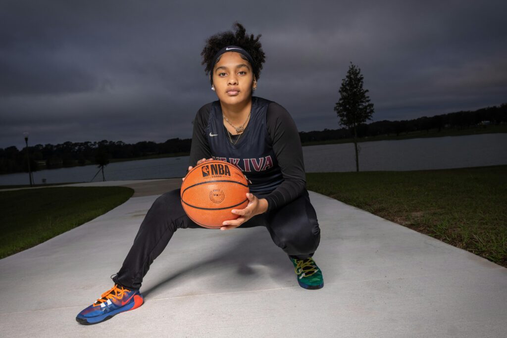Teen athlete holding a basketball outdoors, showcasing sportsmanship and determination.